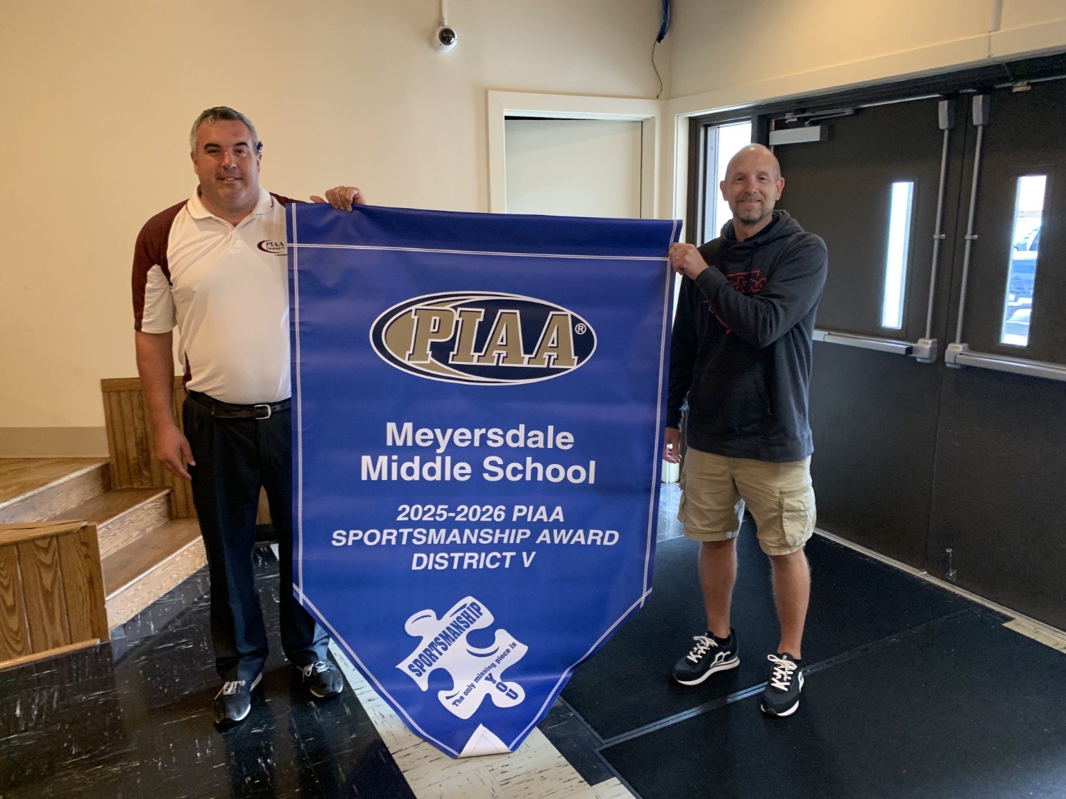 Meyersdale Middle School representative holding a PIAA Sportsmanship Award banner with District V Sportsmanship Chair Todd Best